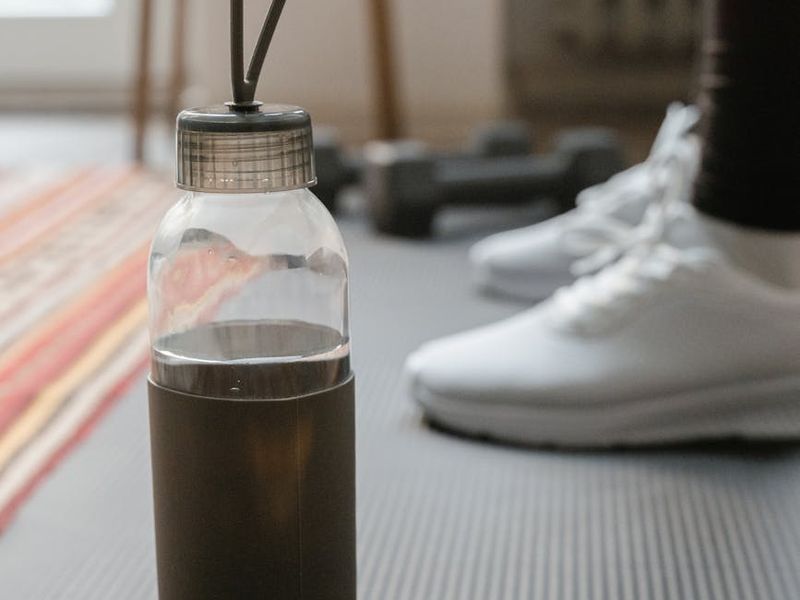 Close up shot of a stopwatch and a water bottle on a gym mat